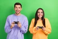 Portrait of two positive funky partners toothy smile enjoy playing video games isolated on green color background Royalty Free Stock Photo