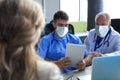 Portrait of two practitioners in face mask consulting patient in hospital