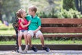 Portrait of two pretty cute children boy and girl having fun time on a bench in summer park outdoors Royalty Free Stock Photo