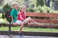 Portrait of two pretty cute children boy and girl having fun time on a bench in summer park outdoors Royalty Free Stock Photo