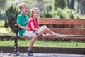 Portrait of two pretty cute children boy and girl having fun time on a bench in summer park outdoors Royalty Free Stock Photo