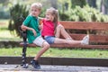 Portrait of two pretty cute children boy and girl having fun time on a bench in summer park outdoors Royalty Free Stock Photo