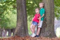 Portrait of two pretty cute children boy and girl standing near big tree trunk in summer park outdoors Royalty Free Stock Photo