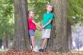 Portrait of two pretty cute children boy and girl standing near big tree trunk in summer park outdoors Royalty Free Stock Photo