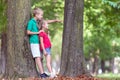 Portrait of two pretty cute children boy and girl standing near big tree trunk in summer park outdoors Royalty Free Stock Photo