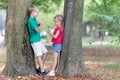 Portrait of two pretty cute children boy and girl standing near big tree trunk in summer park outdoors Royalty Free Stock Photo