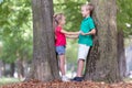 Portrait of two pretty cute children boy and girl standing near big tree trunk in summer park outdoors Royalty Free Stock Photo