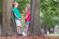 Portrait of two pretty cute children boy and girl standing near big tree trunk in summer park outdoors Royalty Free Stock Photo