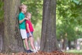 Portrait of two pretty cute children boy and girl standing near big tree trunk in summer park outdoors Royalty Free Stock Photo