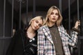 Portrait of two pretty cute teenagers with beautiful lips with blond hair in fashionable jackets outdoors near vintage iron gate. Royalty Free Stock Photo