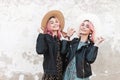Portrait two pretty happy girlfriends in stylish casual clothes in straw trendy vintage hats near white wall in city.Fashion Royalty Free Stock Photo
