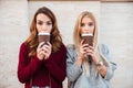 Portrait of a two pretty shocked girls holding coffee cups Royalty Free Stock Photo