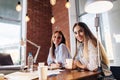 Portrait of two pretty smiling young women looking at camera sitting at work desk. Female freelancers working at home Royalty Free Stock Photo