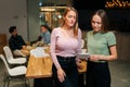 Portrait of two pretty young businesswomen working, talking together, reading paper document, having informal meeting on Royalty Free Stock Photo