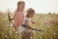 Portrait of two sisters with bouquets of wildflowers. On a warm day, two girls in dresses. Cheerful little daughters are having Royalty Free Stock Photo