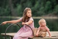 Portrait of two sisters children playing near the water on the background of the lake and the forest. The concept of a happy Royalty Free Stock Photo