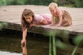 Portrait of two sisters children playing near the water on the background of the lake and the forest. The concept of a happy Royalty Free Stock Photo