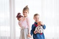 A portrait of two small girls standing and carrying dolls in baby carriers indoors. Royalty Free Stock Photo
