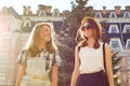 Portrait of two smiling beautiful girls, teenagers 13, 14 years old, close-up, girls talking laughing and walking in summer city