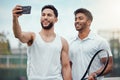 Portrait of two smiling ethnic tennis players taking selfie on cellphone after playing court game. Happy ethnic athletes Royalty Free Stock Photo