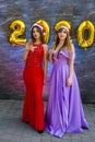 Portrait of two smiling happy girls in christmas dresses posing with gold colored number balloons 2020