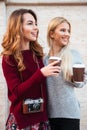 Portrait of two smiling pretty girls with coffee cups Royalty Free Stock Photo