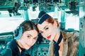 Portrait of two smiling women pilots. Beautiful Smiling Young Woman Pilot Sitting in Cabin of Modern Aircraft Royalty Free Stock Photo