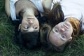 Portrait of two teenage girls friends lying on the grass, a close-up shot from above. Royalty Free Stock Photo