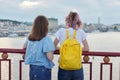 Portrait of two teenage girls standing with their backs on bridge over river Royalty Free Stock Photo