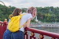 Portrait of two teenage girls standing with their backs on bridge over river Royalty Free Stock Photo