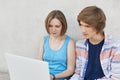 Portrait of two teenagers sitting together looking seriously at laptop reading online book. Fashionable teenage boy and his girlfr Royalty Free Stock Photo