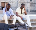 Two upset aframerican tourists sitting outdoors with empty bags