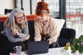 Portrait of two white businesswomen using laptop and smiling, senior woman with glasses and young woman with red hair Royalty Free Stock Photo