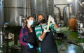 Two winemakers checking winemaking process at factory