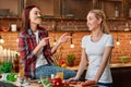 Eat right, Live strong. Young female friends preparing together vegetarian meal in modern kitchen. Cozy interior