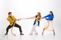 Portrait of two women pulling rope with man symbolizing professional battle, competition isolated over white studio Royalty Free Stock Photo