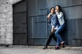 Portrait of two young and attractive women standing next to the wall. Royalty Free Stock Photo