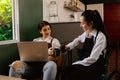 Portrait of two young and beautiful business women sitting with coffee mugs having a good mood chatting while relaxing while worki