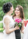 Portrait of two young beautiful women friends talking in green summer park. Pretty females Bride and bridesmaid smiling hugging an Royalty Free Stock Photo