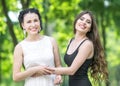 Portrait of two young beautiful women laughing and holding each other`s hands in green summer park. Pretty females Bride and brid Royalty Free Stock Photo