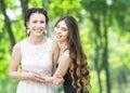 Portrait of two young beautiful women laughing and hugging each other in green summer park. Pretty females bride and bridesmaid sm Royalty Free Stock Photo