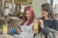 Portrait of two young beautiful women using mobile phone at coffee shop. Royalty Free Stock Photo