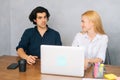 Portrait of two young business people sitting at desk in office using laptop and discussing project. Front view of Royalty Free Stock Photo