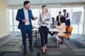 Portrait of two young businesspeople using digital tablet while colleague in background. Royalty Free Stock Photo