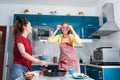 Portrait of two young Caucasian women cook pizza in the kitchen and have fun together. Indoors. Concept of family Royalty Free Stock Photo