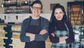 Portrait of two coffee house owners attractive young people standing inside coffee-shop, smiling and looking at camera Royalty Free Stock Photo