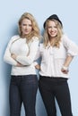 Portrait of two young female friends standing together against light blue background Royalty Free Stock Photo