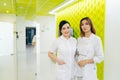 Portrait of two young female nurses wearing medical scrubs smiling looking at camera standing posing on hallway at Royalty Free Stock Photo