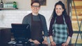 Portrait of two young good-looking waiters standing at cashier's desk in coffee-house and smiling. Successful Royalty Free Stock Photo