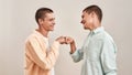 Portrait of two young happy twin brothers looking at each other and giving fist bump while standing face to face Royalty Free Stock Photo